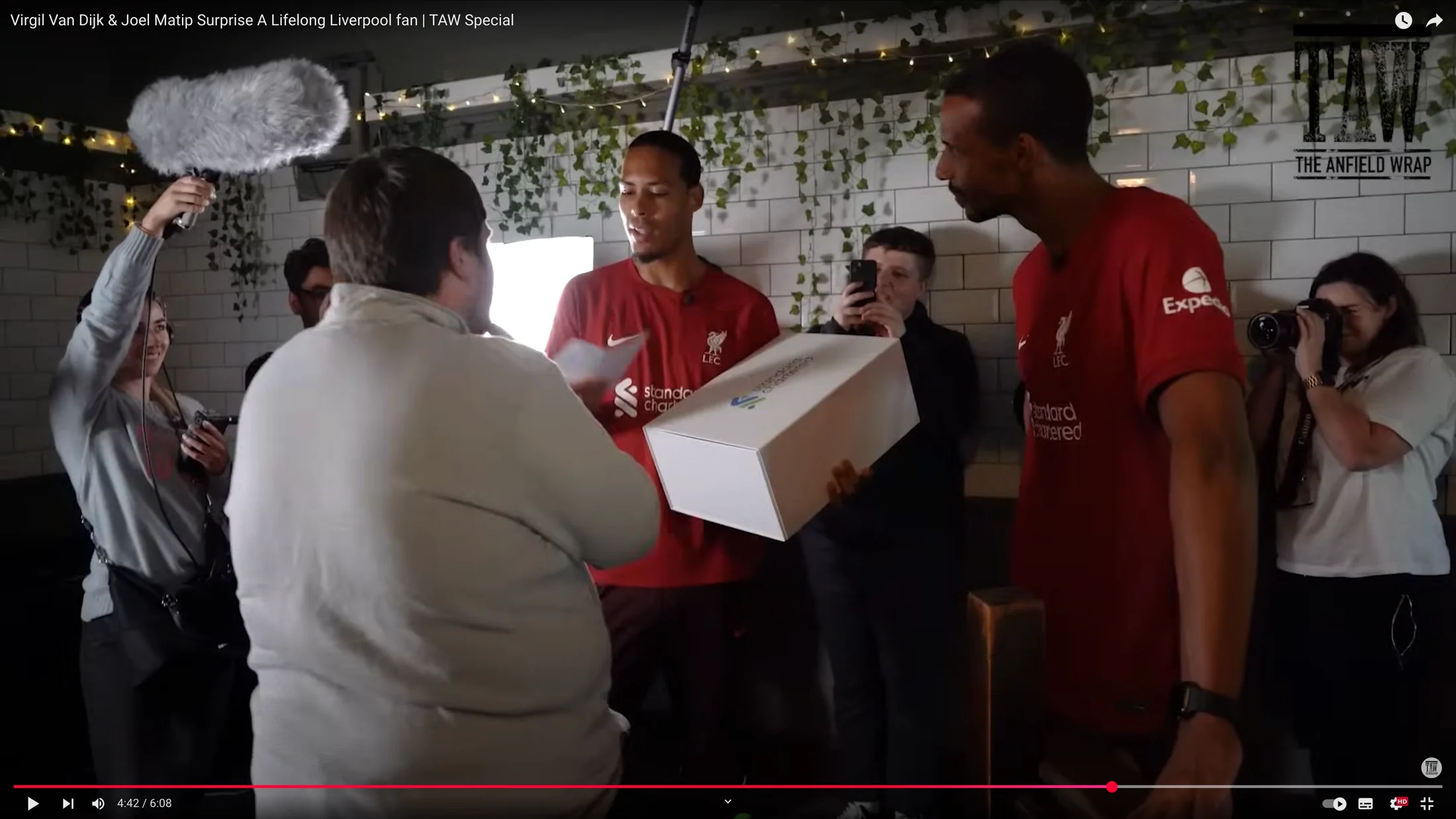 Liverpool players surprising a supporter with a Standard Chartered prize